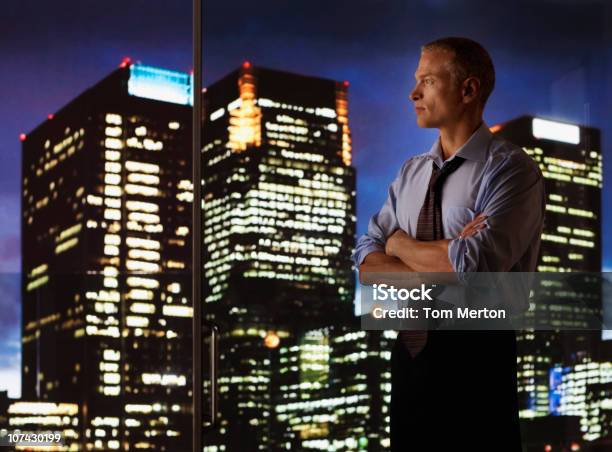 Empresário Sério Olhando Para A Parede De Vidro Com Vista Da Cidade À Noite - Fotografias de stock e mais imagens de Vista de Ângulo Baixo