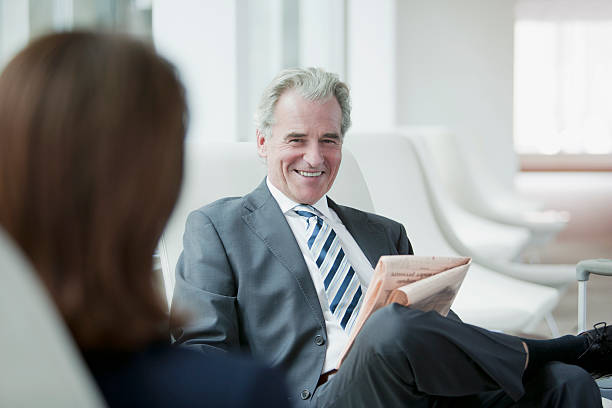 Businessman reading newspaper in waiting area  newspaper airport reading business person stock pictures, royalty-free photos & images