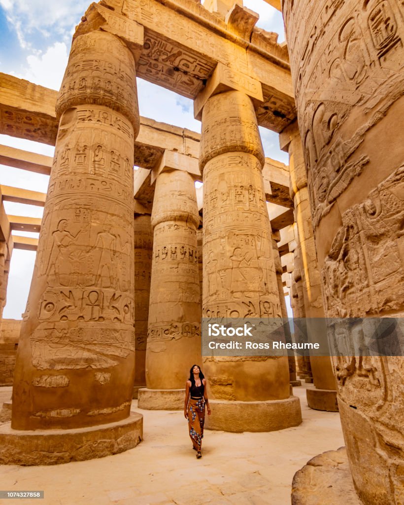 EXPLORING ANCIENT EGYPTIAN TEMPLES Young female traveller wandering through ancient Karnak Temple. Beautiful Egyptian landmark with hieroglyphics. Travelling woman adventuring around the world. Luxor, Egypt Egypt Stock Photo