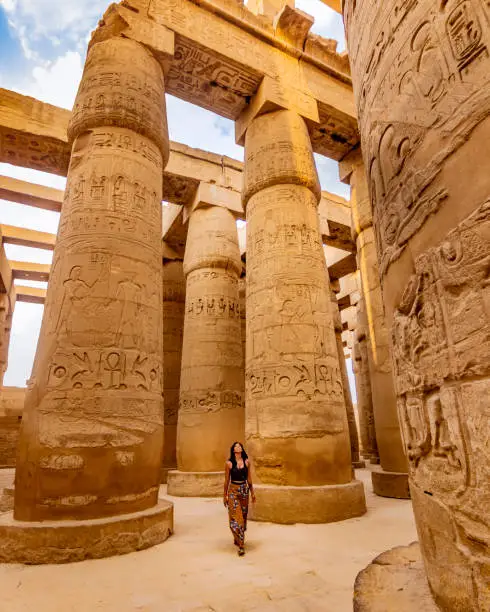 Young female traveller wandering through ancient Karnak Temple. Beautiful Egyptian landmark with hieroglyphics. Travelling woman adventuring around the world. Luxor, Egypt