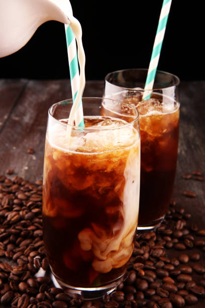 istock Ice coffee on a rustic table with cream being poured into it showing the texture and refreshing look of the drink 1074332248