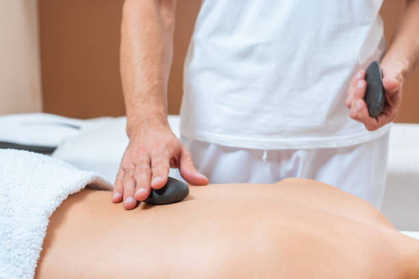 cerca de masajista masculino poniendo piedras calientes en espalda de mujer - lastone therapy men spa treatment male fotografías e imágenes de stock