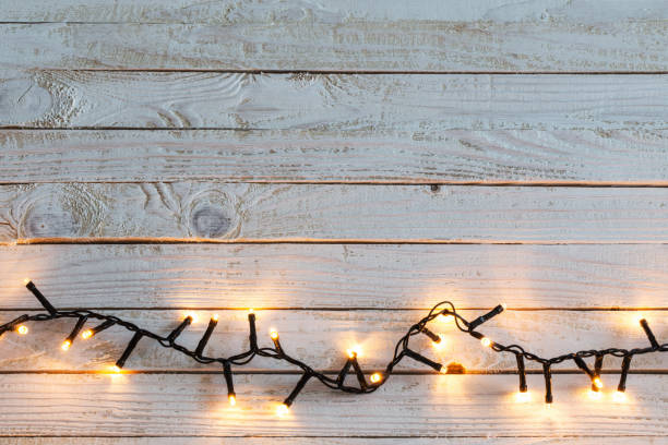 istock Christmas lights on white wooden background 1074348756