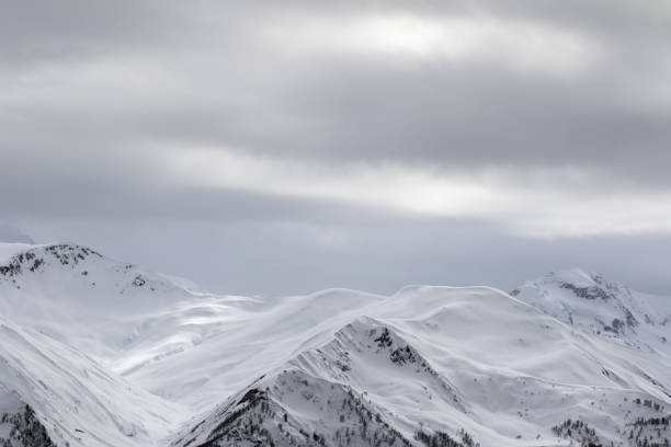 istock Sunlight snowy mountains in fog and gray overcast sky 1074349844
