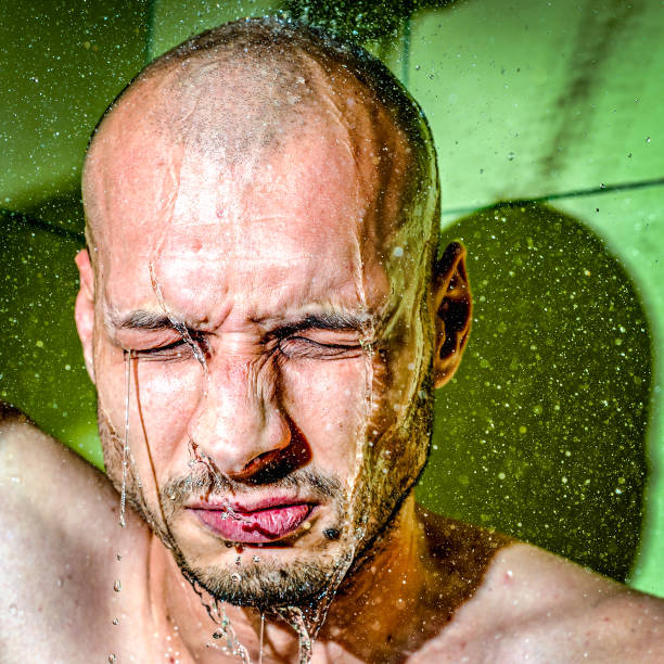 男は自分自身に彼の仕事でハード イライラと緊張の一日クローズ アップ後落ち着いて仕事の後、冷たいシャワーを与える - men naked shower bathroom ストックフォトと画像
