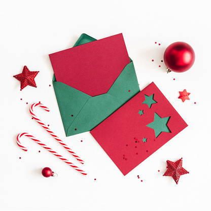 Christmas composition. Envelope, paper card, red decorations on white background. Christmas, winter, new year concept. Flat lay, top view, copy space, square