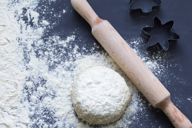istock fresh raw pastry dough, rolling pin and cookie cutters on dark background 1074401934