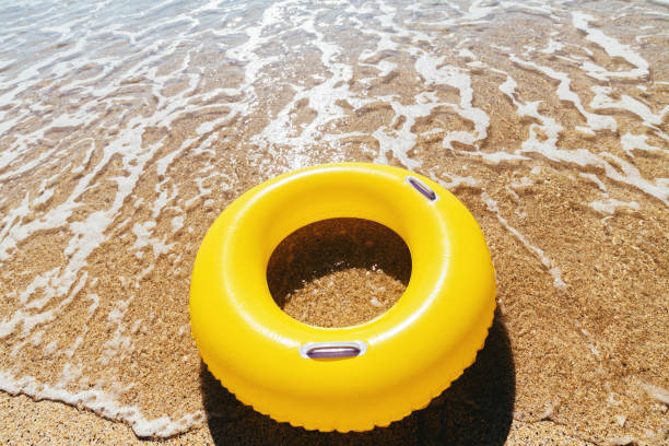 istock Yellow rubber ring on a breaking wave at the waters edge, Pedn Vounder Beach, Cornwall on a bright sunny day. 1074413840