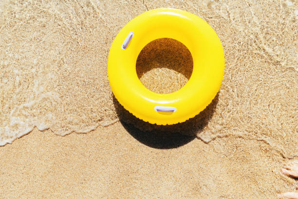istock Yellow rubber ring on a breaking wave at the waters edge, Pedn Vounder Beach, Cornwall on a bright sunny day. 1074413850