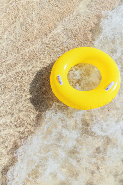 istock Yellow rubber ring on a breaking wave at the waters edge, Pedn Vounder Beach, Cornwall on a bright sunny day. 1074413868