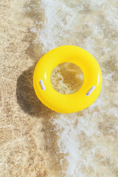 istock Yellow rubber ring on a breaking wave at the waters edge, Pedn Vounder Beach, Cornwall on a bright sunny day. 1074413874