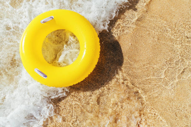 istock Yellow rubber ring on a breaking wave at the waters edge, Pedn Vounder Beach, Cornwall on a bright sunny day. 1074413892