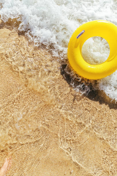 istock Yellow rubber ring on a breaking wave at the waters edge, Pedn Vounder Beach, Cornwall on a bright sunny day. 1074413902