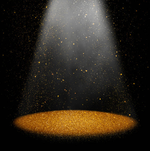 Twinkling gold glitter falling on the stage illuminated with one spot light
