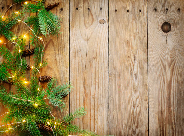 istock Christmas background with fir tree branches and lights on wooden board. 1074436428
