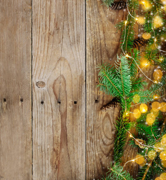 istock Christmas background with fir tree branches and lights on wooden board 1074436712
