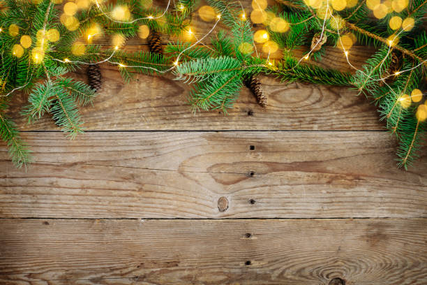 istock Christmas background with fir tree branches and lights on wooden board 1074456954