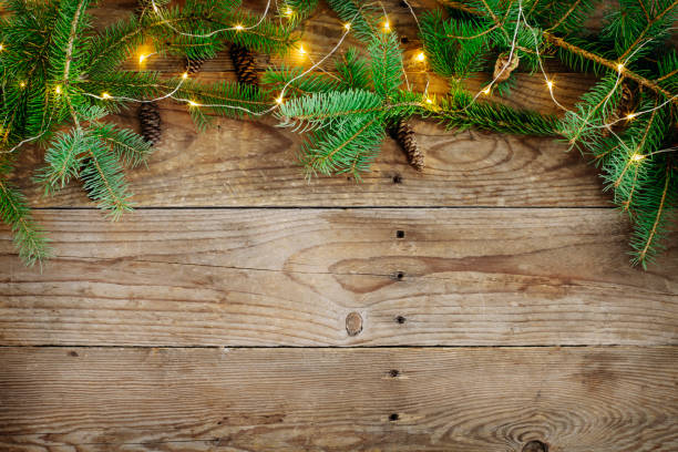 istock Christmas background with fir tree branches and lights on wooden board 1074457362