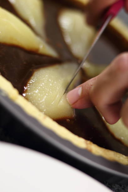 istock Chef cutting pears in chocolate filling with knife 1074473742