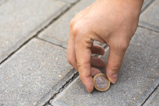 Female hand picking one euro coin from the ground stock photo