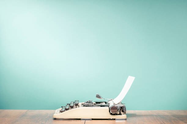 retro classic typewriter from circa 1950s with sheet of paper on wooden desk front aquamarine wall background. vintage old style filtered photo - book school desk old imagens e fotografias de stock