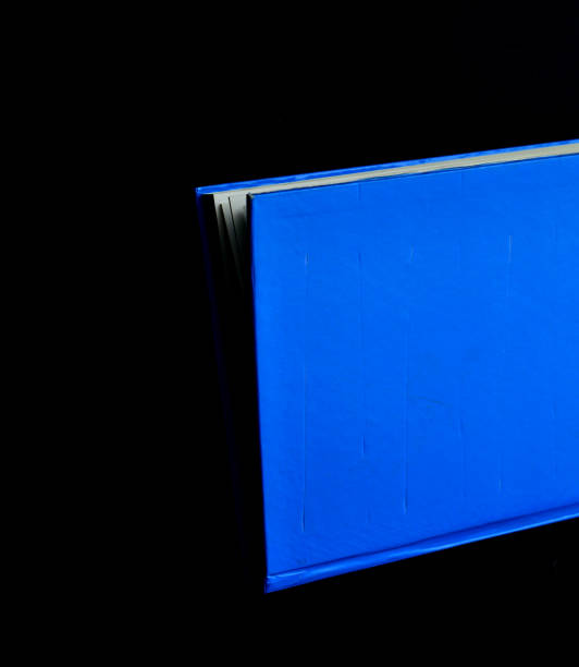 istock blue book on a black background, isolated 1074506624