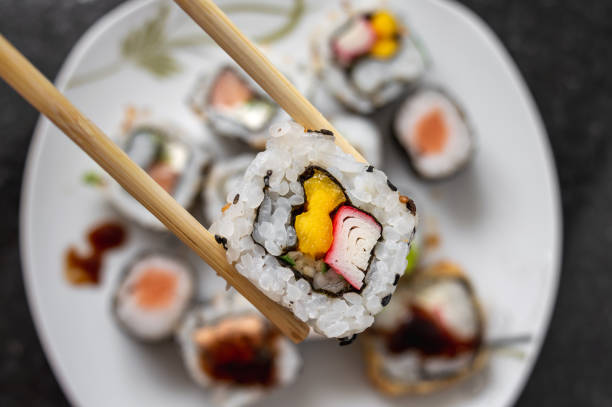 tomar un alimento japonés california roll con palillos - seafood salmon ready to eat prepared fish fotografías e imágenes de stock