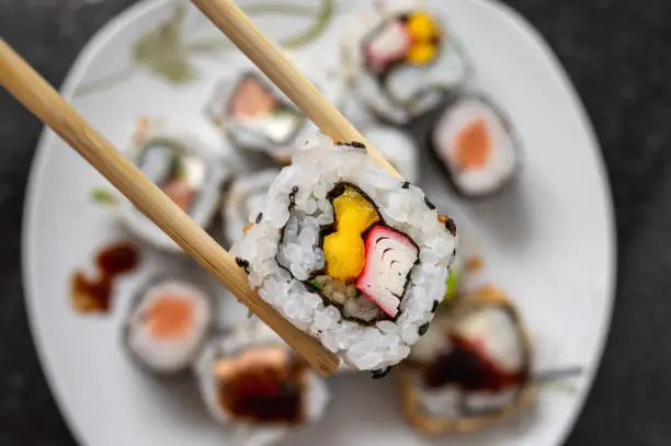 Grabbing a california roll japanese food with chopstick - top view