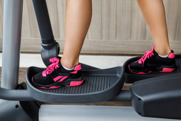 istock Female legs on a elliptical trainer in the gym 1074509428