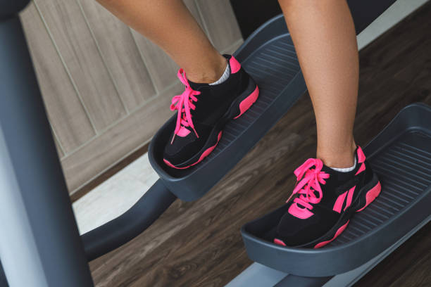 istock Female legs on a elliptical trainer in the gym 1074509442