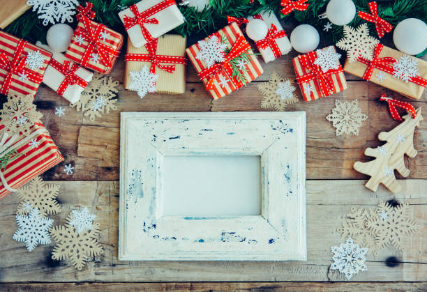 istock Christmas background with white vintage frame decorations and gift boxes on the wooden table. 1074515306