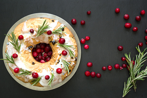 Traditional homemade Christmas cake decorated cranberry berry and rosemary on plate. View from above with copy space.