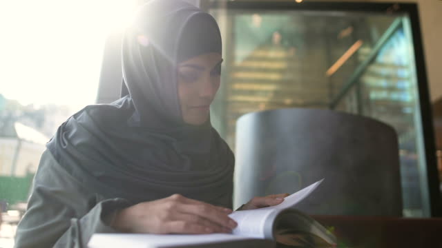 Self-confident Arabic lady reading book in cafe, education and self-development