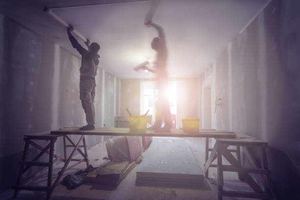 Workers are installing ceiling from wooden scaffolding  platform in apartment is under construction, remodeling, renovation, extension, restoration, overhaul and reconstruction.