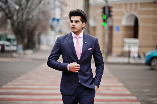 Elegant indian macho man model on suit and pink tie walking at cross pedestrian.