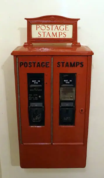 A wall mounted, coin operated postage stamp machine.