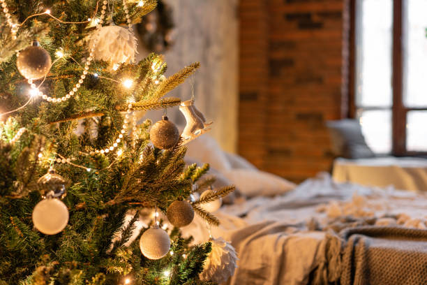 istock Fir Branches decorated in the foreground. Loft apartments, brick wall with candles and Christmas tree. Bed in the bedroom, high large Windows 1074547666