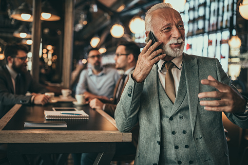 Senior businessman using phone at the pub