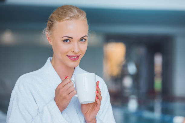 istock smiling attractive blonde woman holding white cup in spa 1074606014