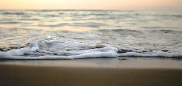 Small and frothy waves on the shore during sunrise or sunset in summer.