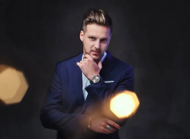 Photo of A man dressed in a suit over dark grey background.