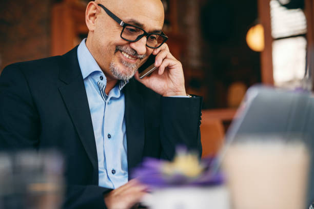 istock Senior businessman using smart phone and laptop while sitting in cafe. Coffee on the table. 1074625090