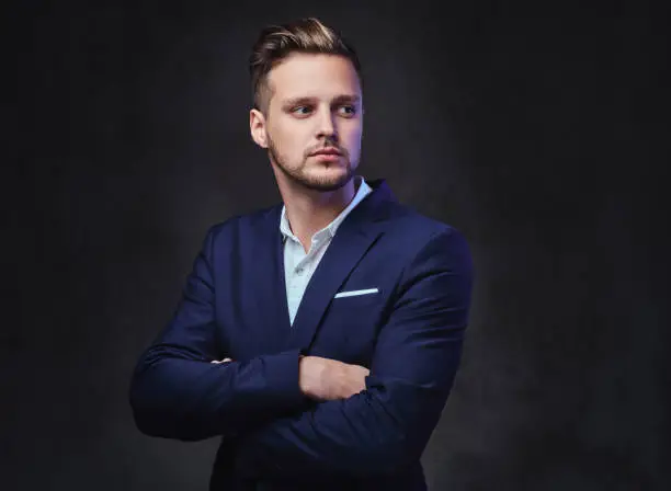 Photo of A man dressed in a suit over dark grey background.