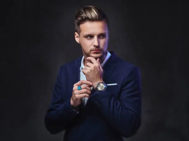 Photo of A man dressed in a suit over dark grey background.