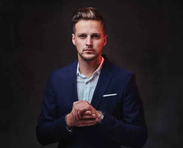 Photo of A man dressed in a suit over dark grey background.