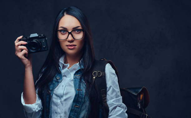 istock A woman with backpack holds compact photo camera. 1074643696