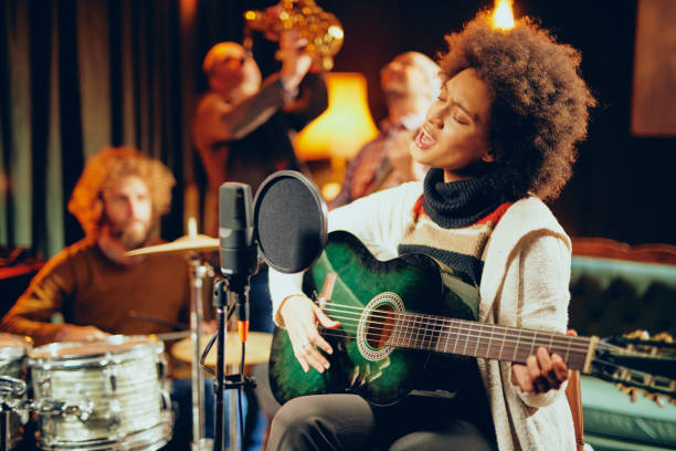istock Mixed race woman singing and playing guitar 1074647912