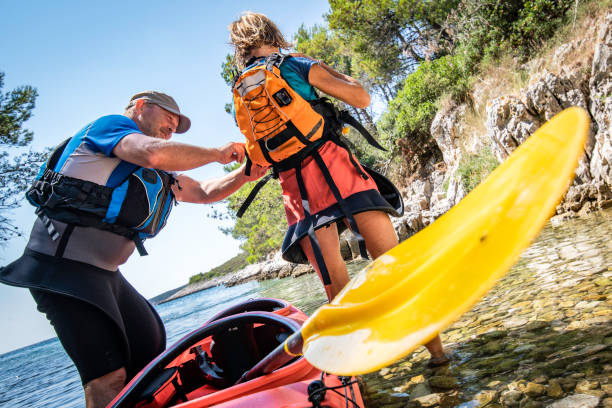 эксперт байдарочник помогает женщине надеть спасательный жилет - women kayaking life jacket kayak стоковые фото и изображения