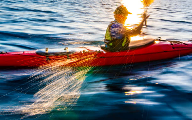 Side view of a motion blurred kayaker rowing at sea.