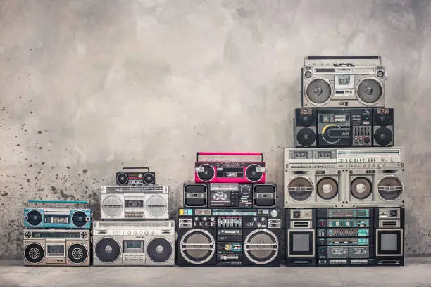 Photo of Retro old school design ghetto blaster boombox stereo radio cassette tape recorders tower from circa 1980s front aged concrete wall background. Vintage style filtered photo